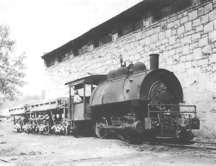 Black and white photo of train engine car in front of brick building