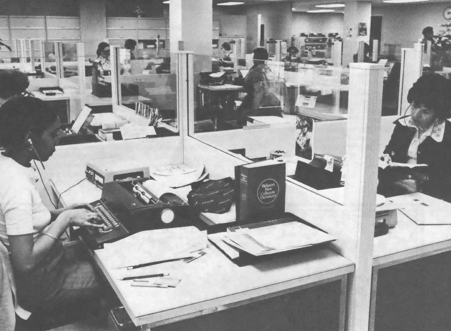 Black and white photo of women working at desks in open office space