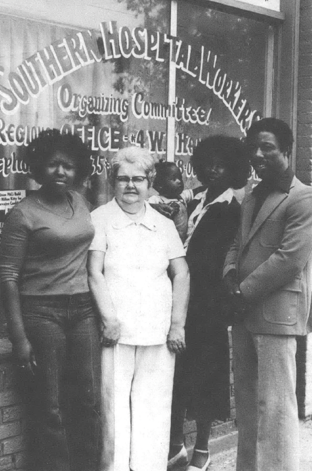 Black and white photo of women standing in front of a window