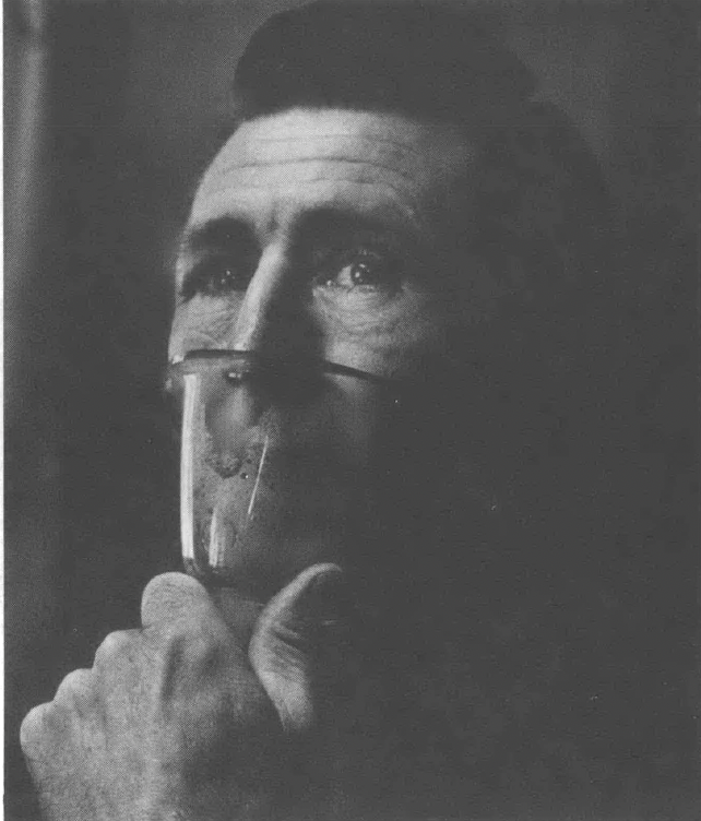 Black and white portrait of man with oxygen mask held up to his face