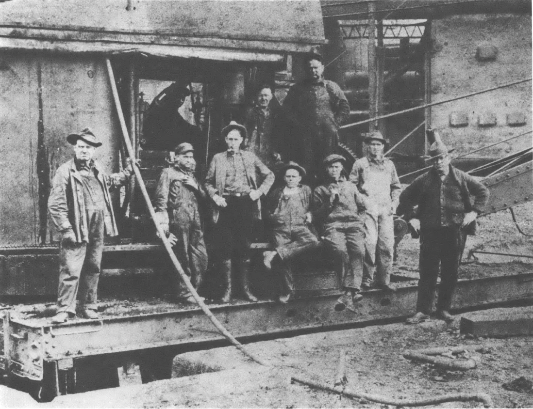 Nine men pose for a photo in a construction site standing on steel structures