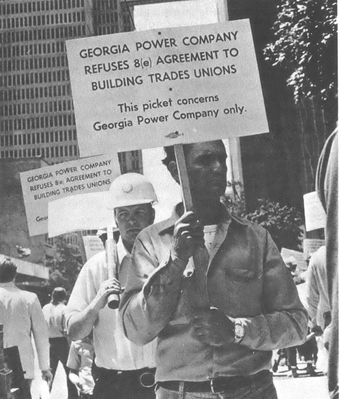 Black and white photo of two people holding signs picketing the Georgia Power Company