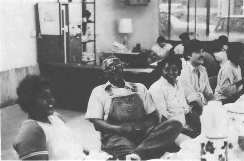 Several people, two Black women, one Black man, and one white man, pictured sitting and talking at a larger table