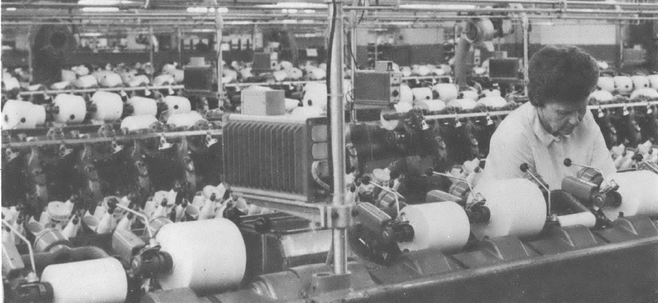 Black and white photo of older white woman with short hair working at a loom