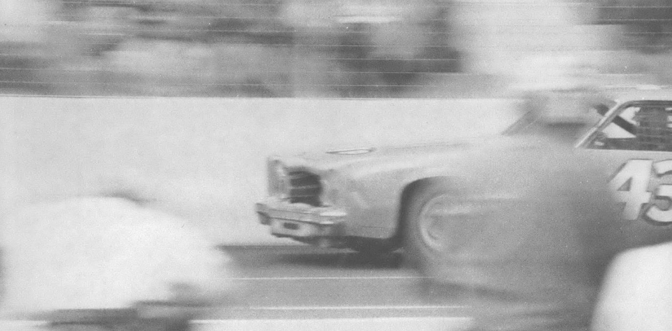 Black and white photo of racing car in motion on track