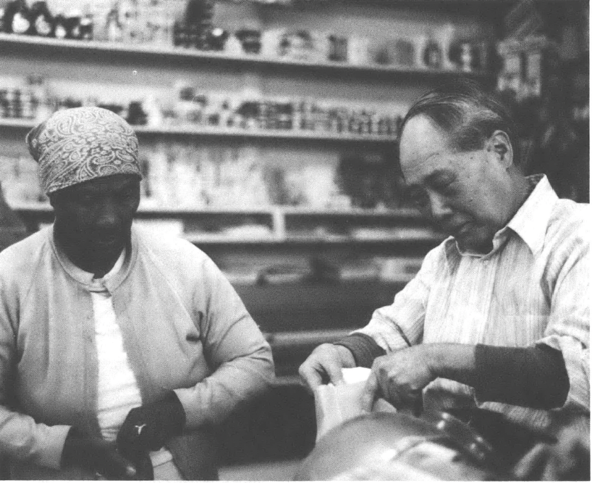 A black and white photo of Sui U. Chow at his store next to an unnamed Black woman