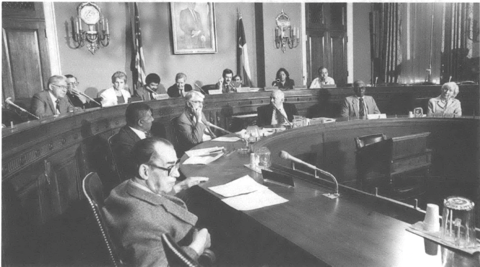 People in a legislative chamber or conference room of some kind