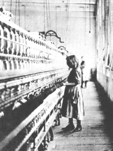 Black and white photo of young girl standing at loom in factory