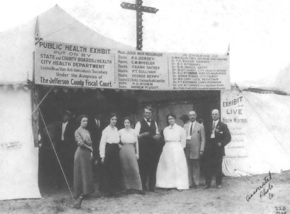 Black and white photo of people in nineteenth century dress standing in front of a church