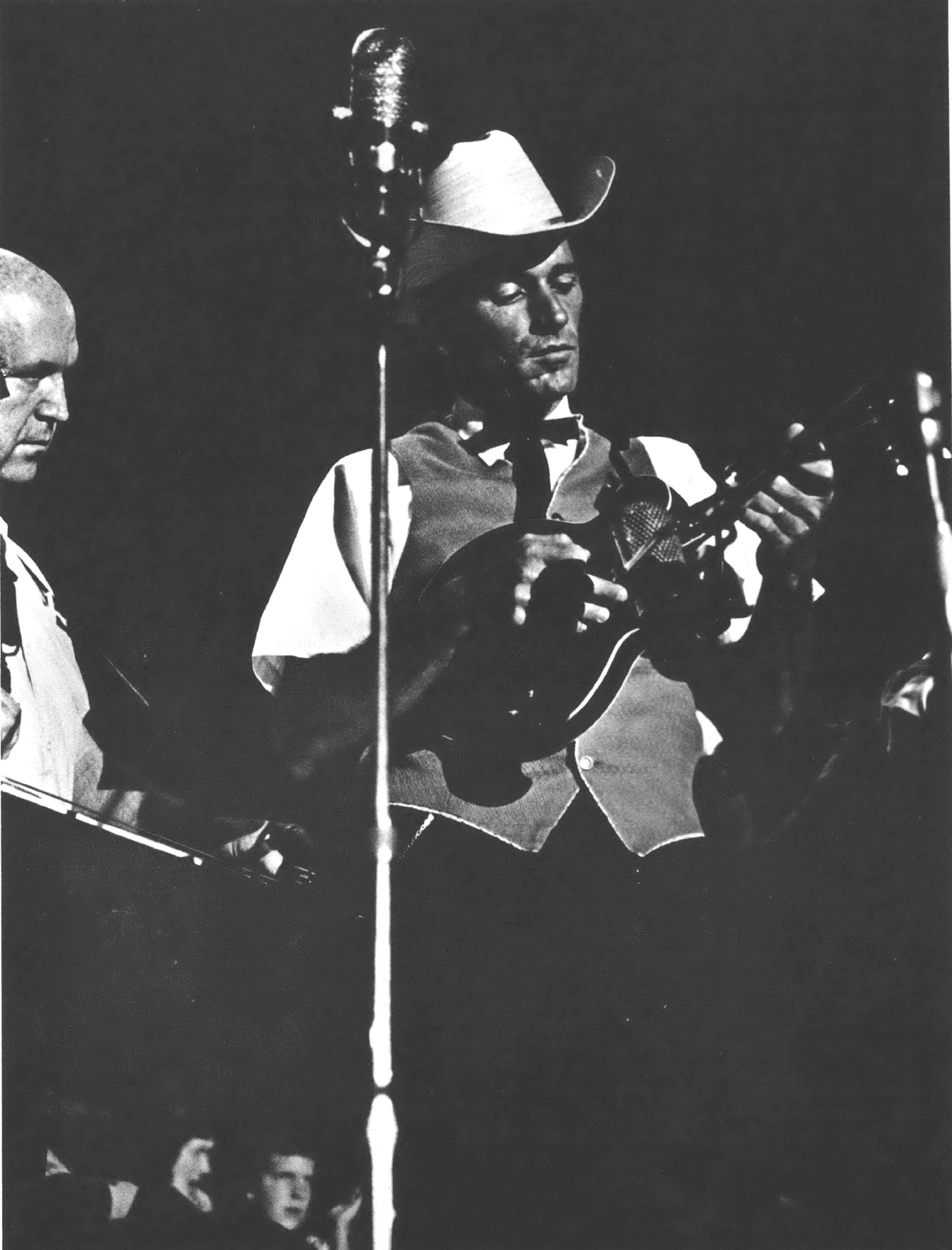 Black and white photo of white man playing mandolin and wearing a cowboy hat