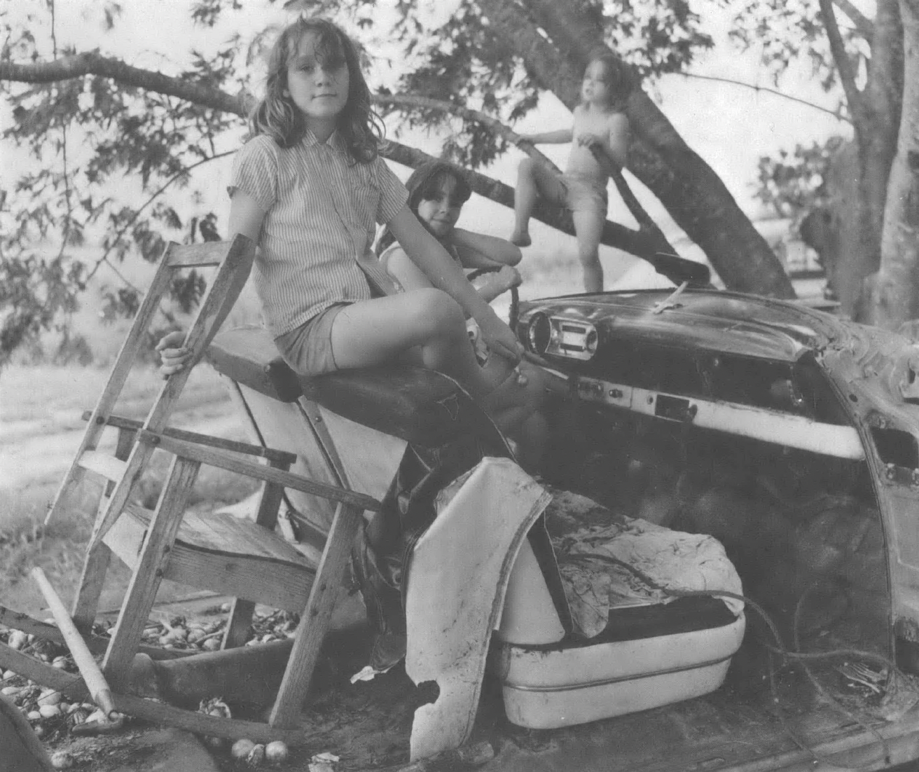 Black and white photo of white child sitting on a wooden playset outside