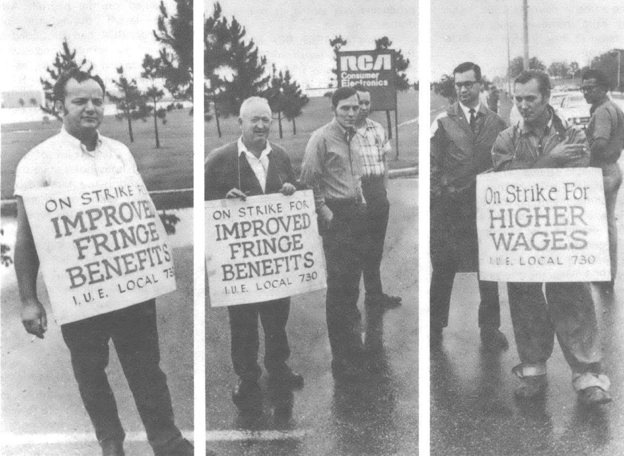 Black and white photo of three men standing with signs around their neck