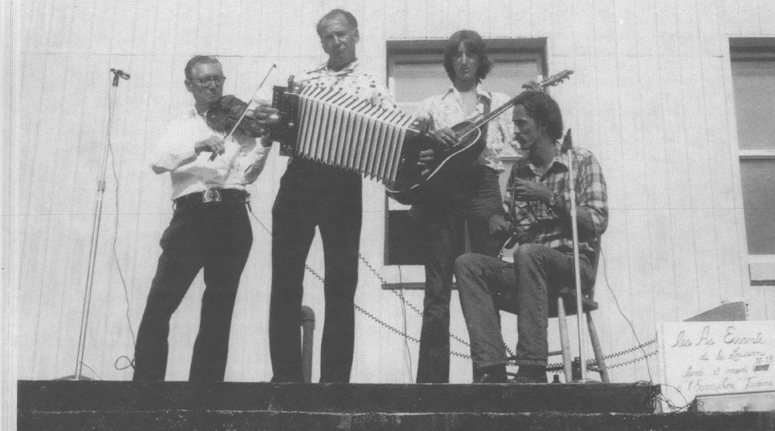 Photo of band with guitar, accordion, fiddle playing on stage