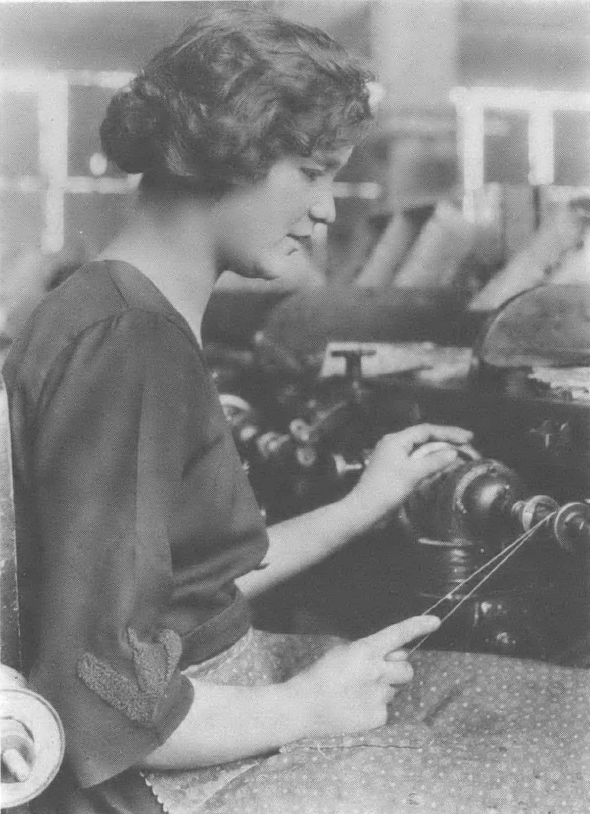 Black and white photo of woman standing at machine