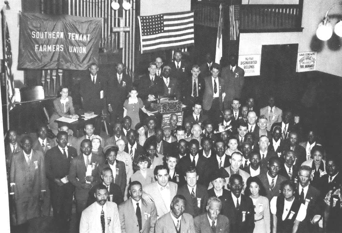 Black and white photo of a gathering of people standing inside a church