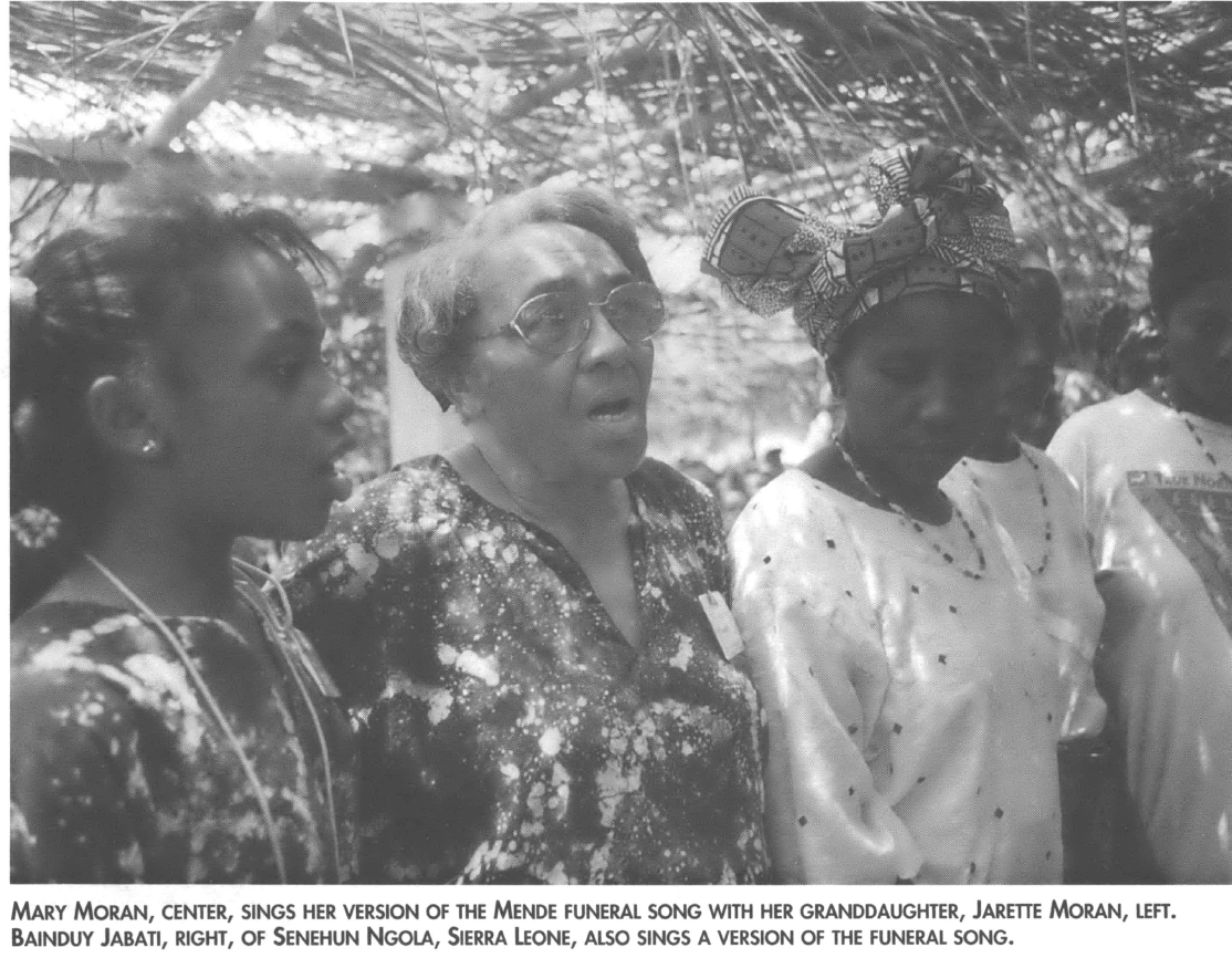 Several generations of Black women singing under a tree