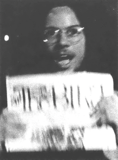 Black and white photo of a man in eyeglasses holding up a copy of The Great Speckled Bird