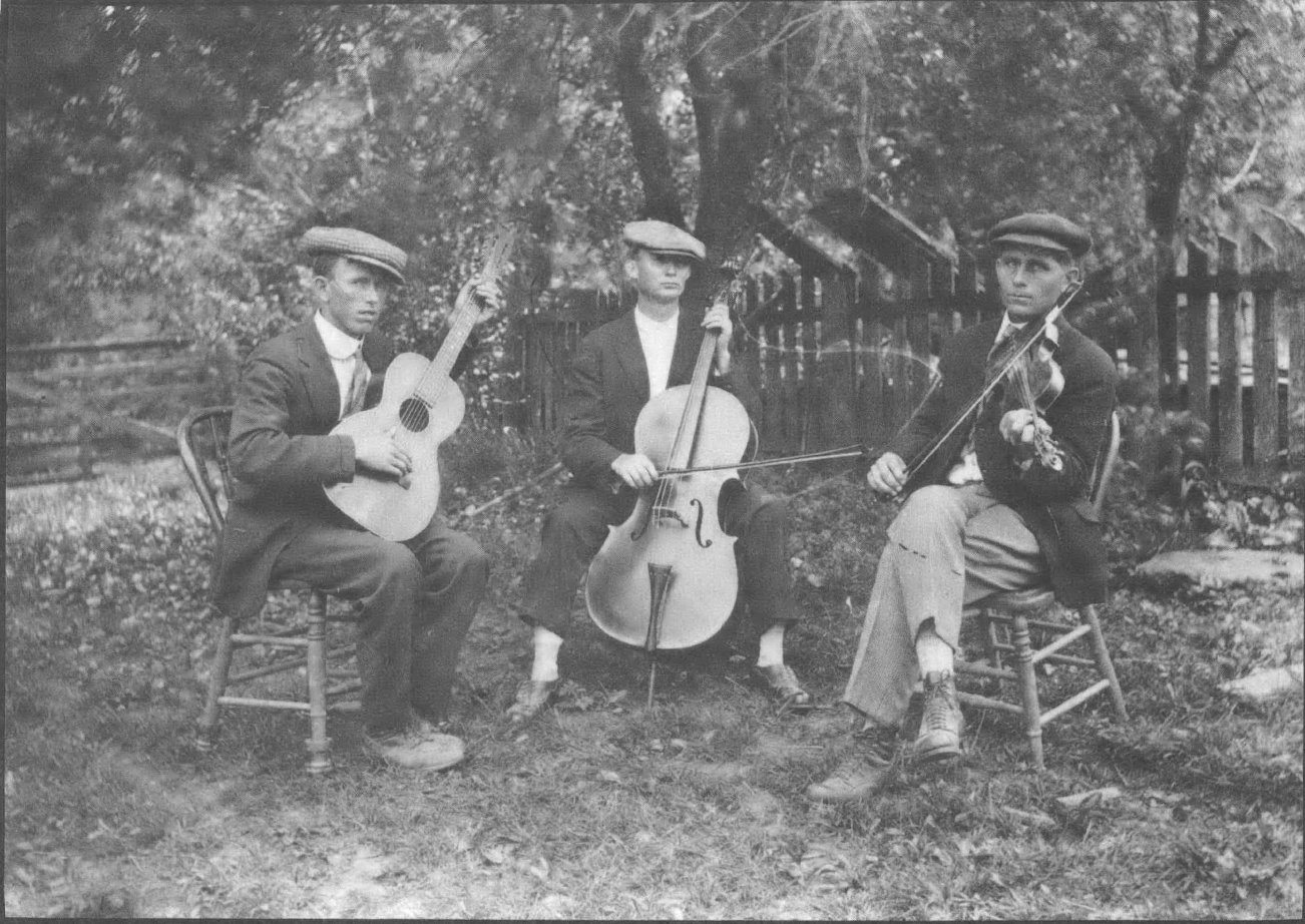 Black and white photo of all-white string band in nineteenth century or early twentieth dress, seated outside in a playing circle