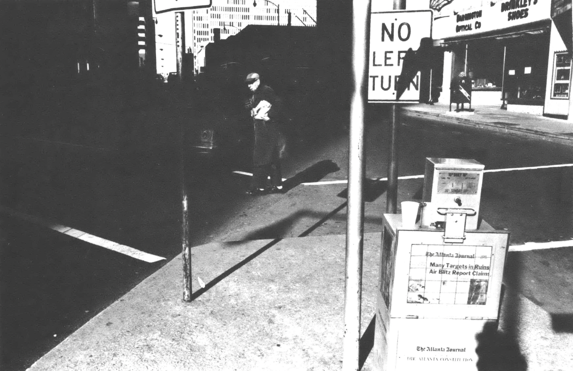 Man walking in city street near newspaper box