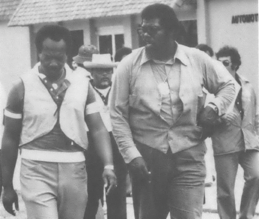 Black and white photo of two Black men in aviators walking down a street