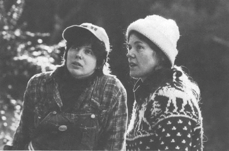 Black and white picture of two women in hats, one in overalls and one in a sweater