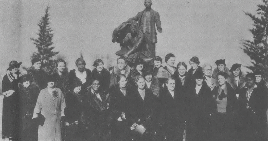 Black and white nineteenth century photo of group of white women standing in front of monument