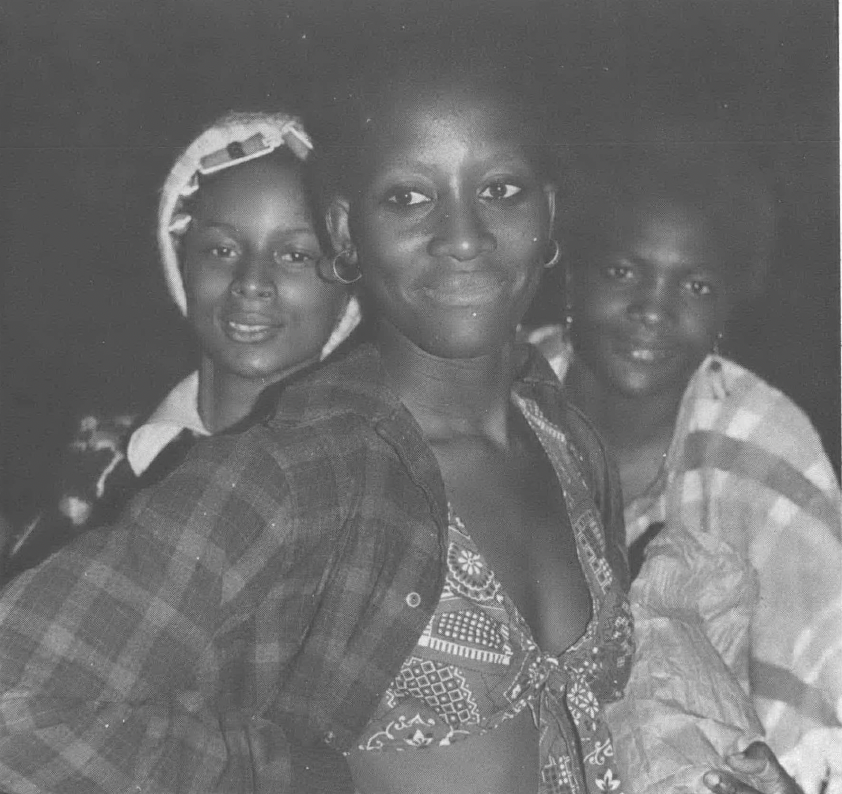 Black and white photo of three young Black women smiling at camera