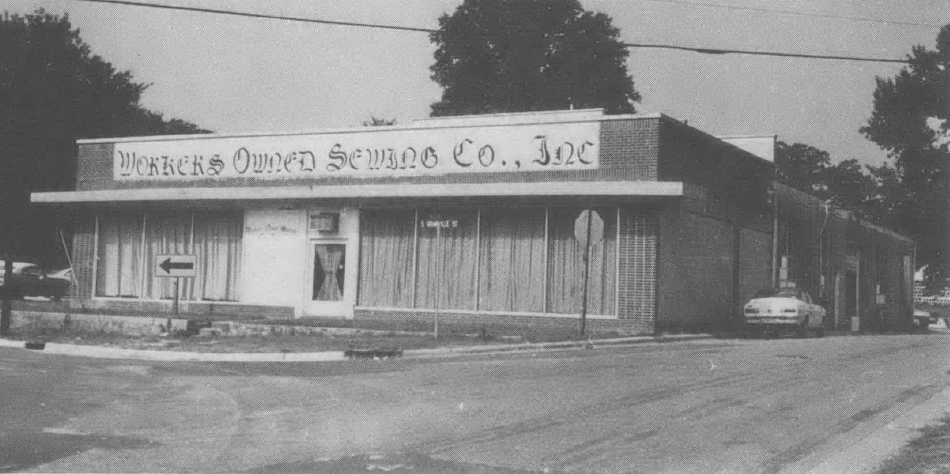 Black and white photo of Workers' Owned Sewing Co. one-story building and empty parking lot