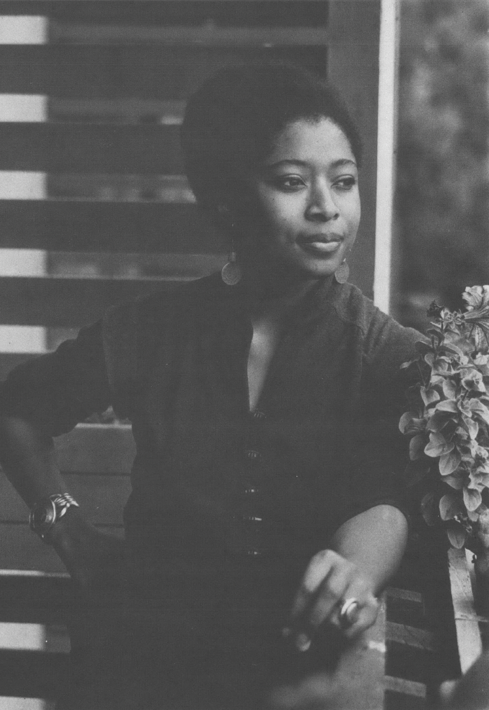 Black and white photo of Alice Walker leaning on porch railing looking into distance