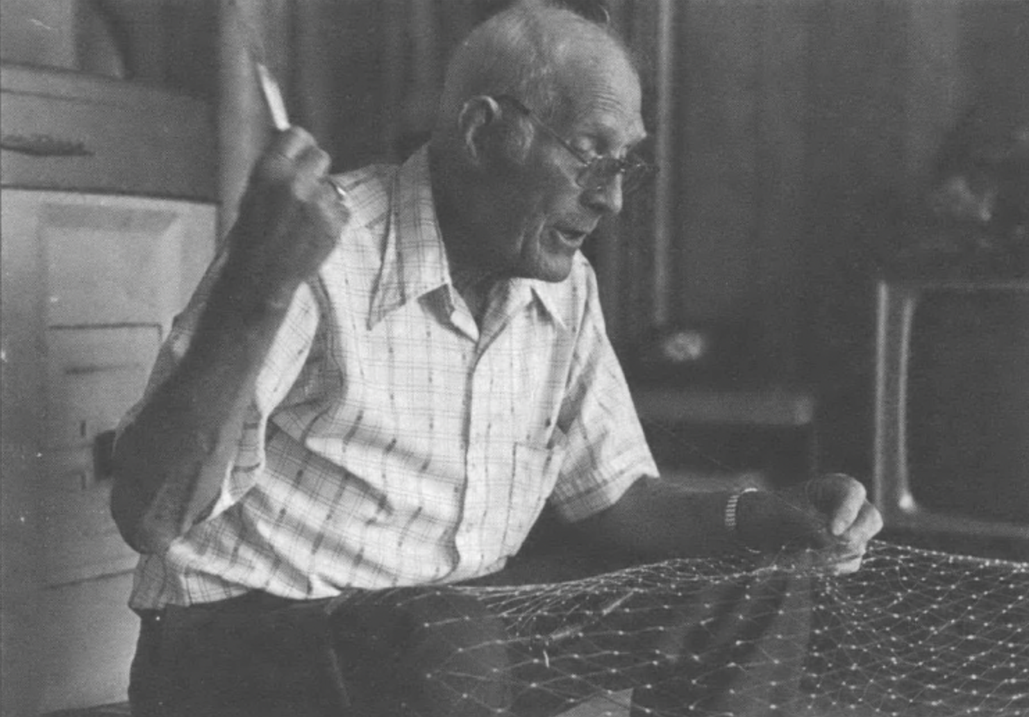 Earl Guthrie sewing a cast net in living room