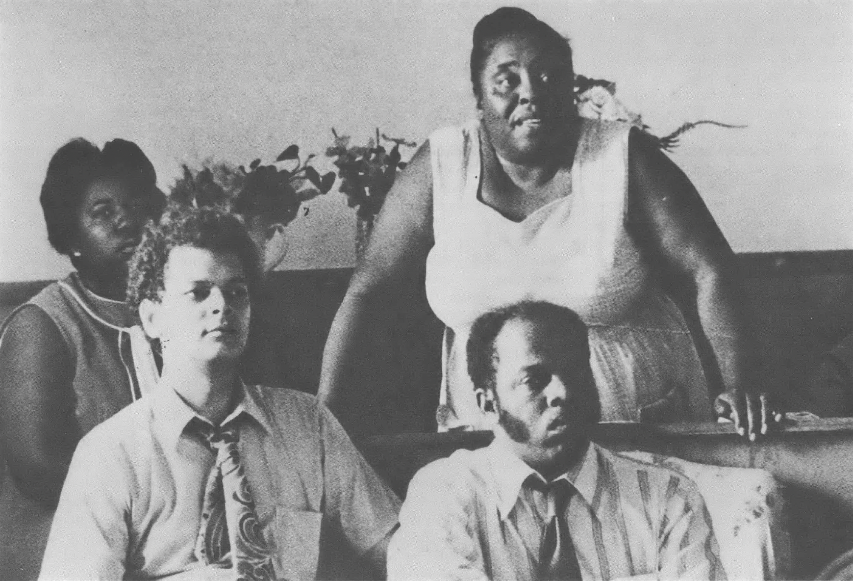 A black and white photo of Annie Divine, Fannie Lou Hamer, Julian Bond, and John Lewis seated at an event.