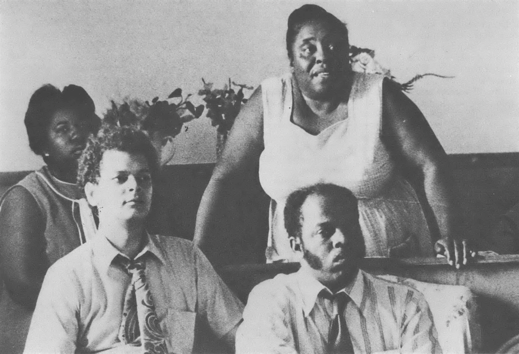 A black and white photo of Annie Divine, Fannie Lou Hamer, Julian Bond, and John Lewis seated at an event. 