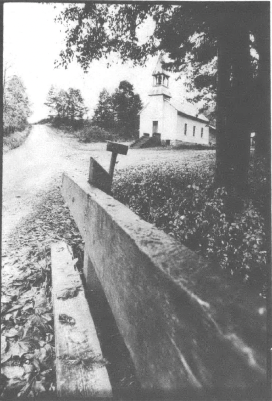 black-and-white photograph of a road with a church in the backgrounf