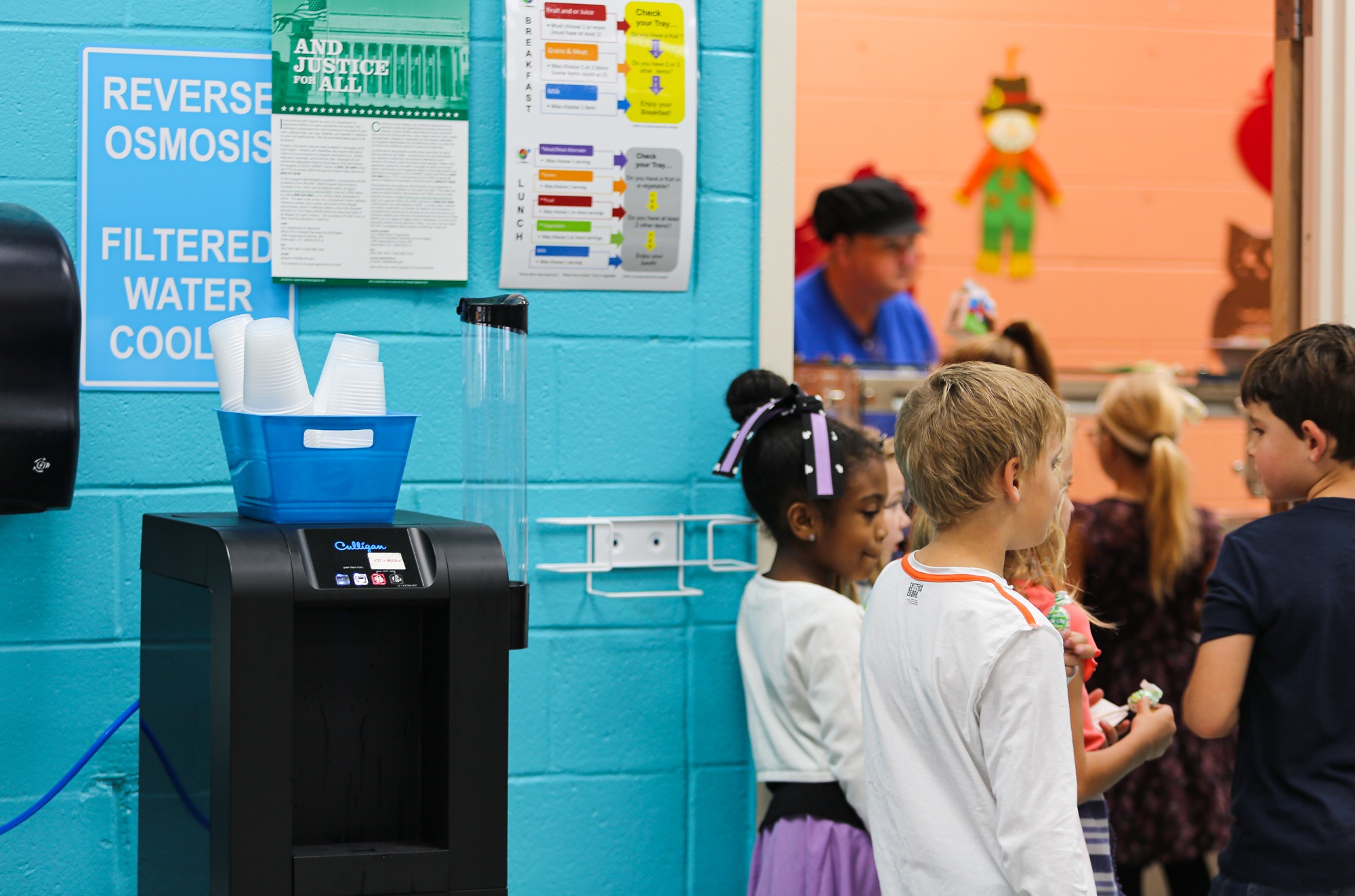 Children in school hallway standing near reverse osmosis water filtration drinking station