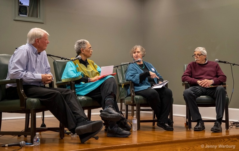 Four people sitting in chairs on a stage