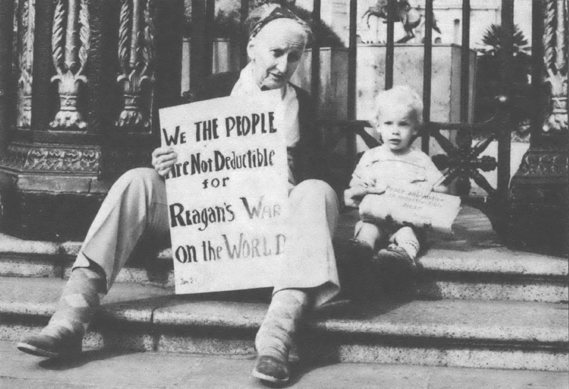 Woman, holding poster, and child sitting on steps