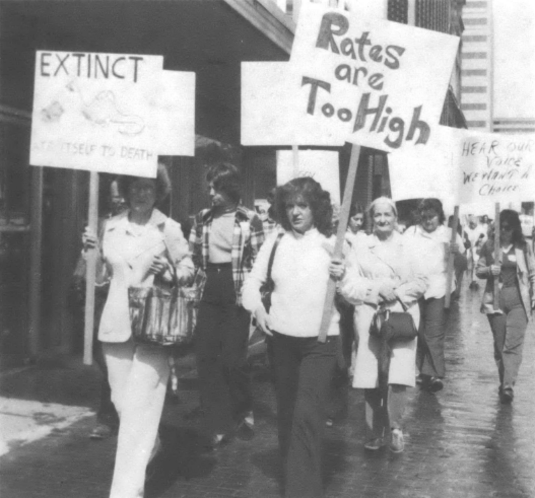 protesters carrying signs, including "Rates are too high"