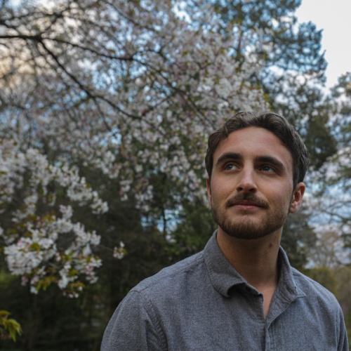 Head and shoulders shot of Alasdair McNinch in front of a white flowering tree