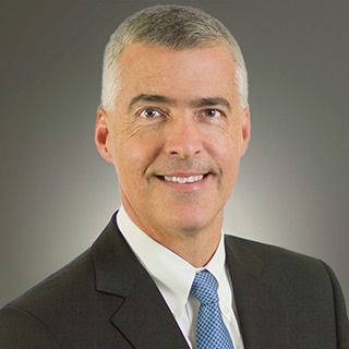 Head shot of a silver-haired white man in a suit jacket and tie