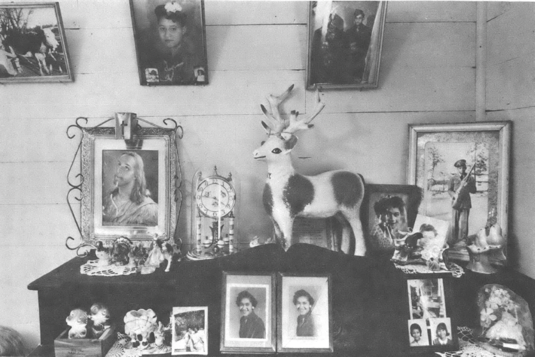 Black and white photo of display of photos on a mantel and wall