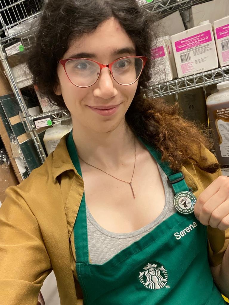 Woman in Starbucks apron showing Starbucks Workers United pin