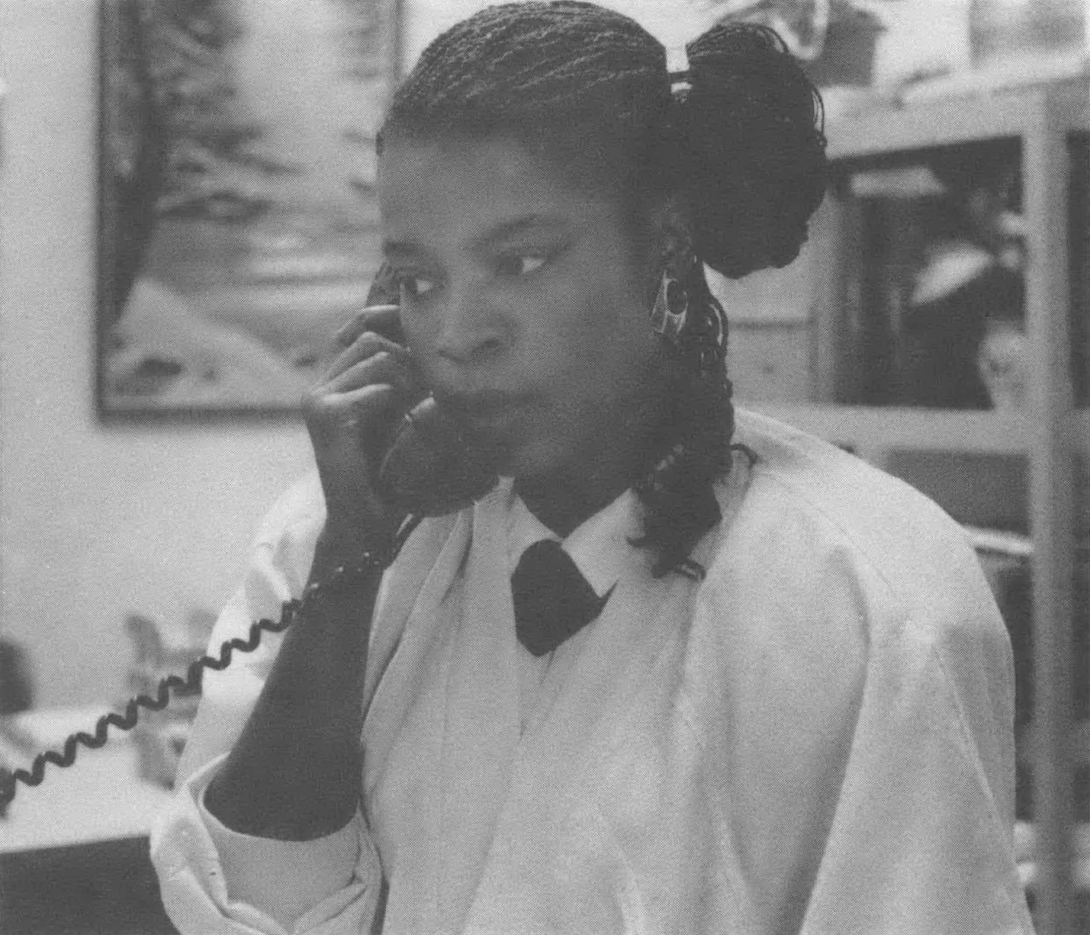 Black and white photo of a Black woman on the phone in an office. 